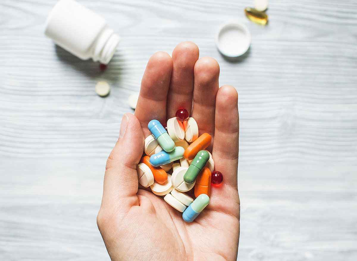 Bunte Pillen und Medizin in der Hand