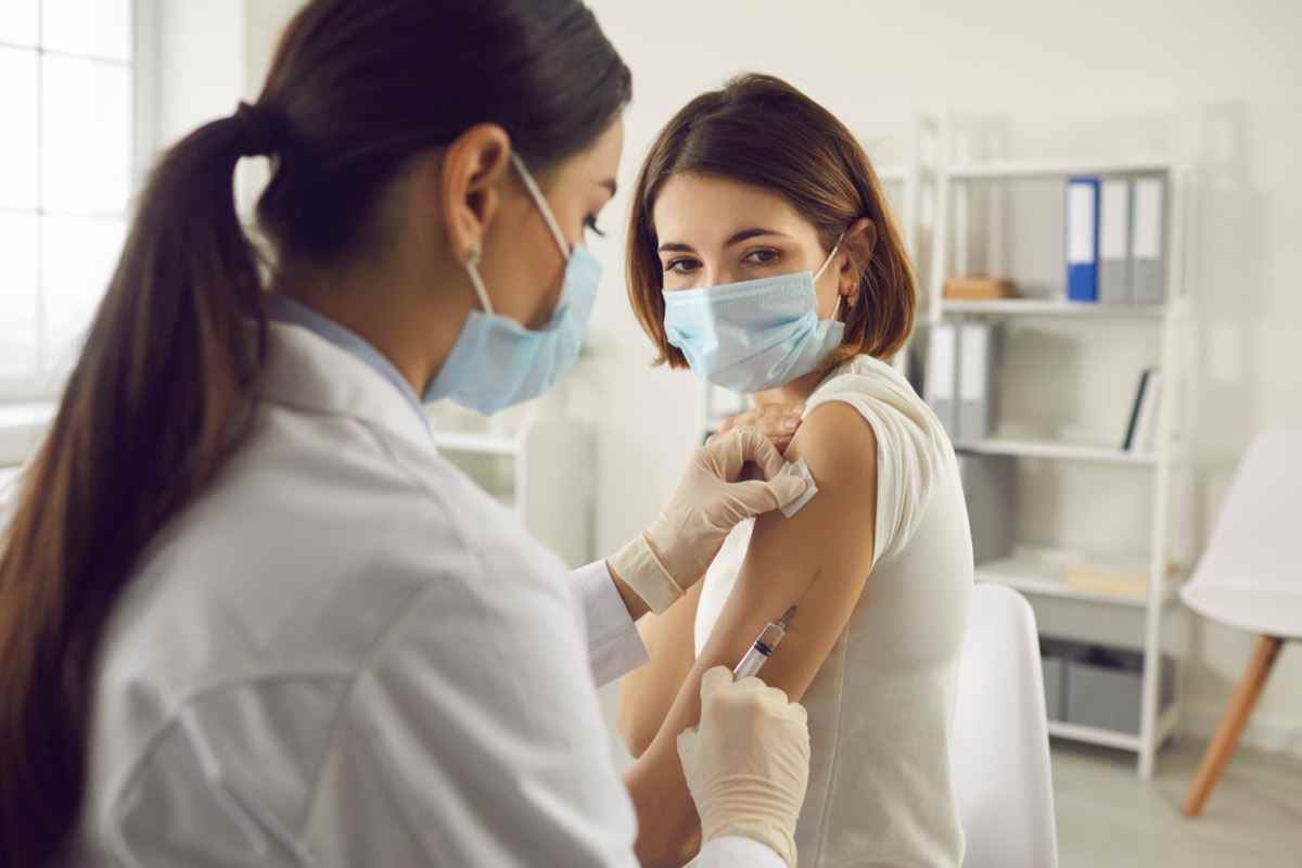 Frau in medizinischer Gesichtsmaske, die im Krankenhaus einen Covid-19-Impfstoff erhält