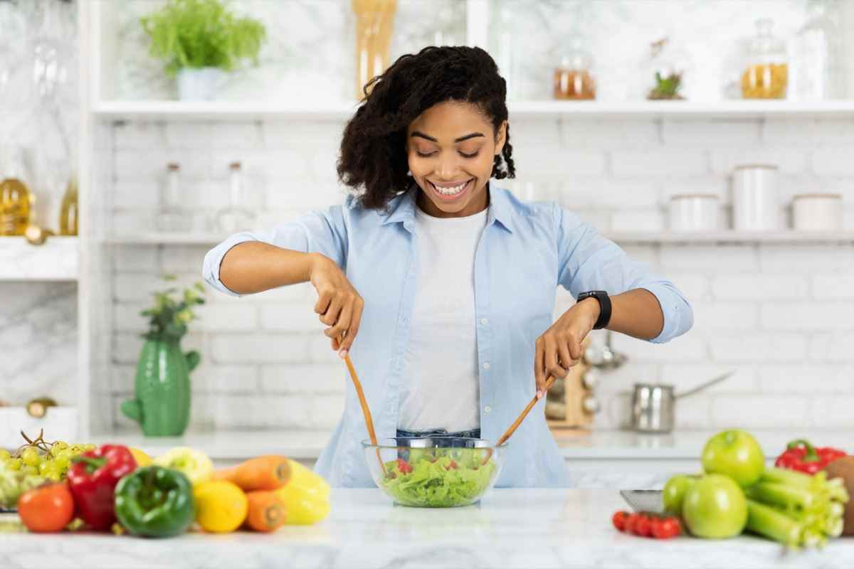 Frau bereitet Gemüsesalat in moderner Küche zu