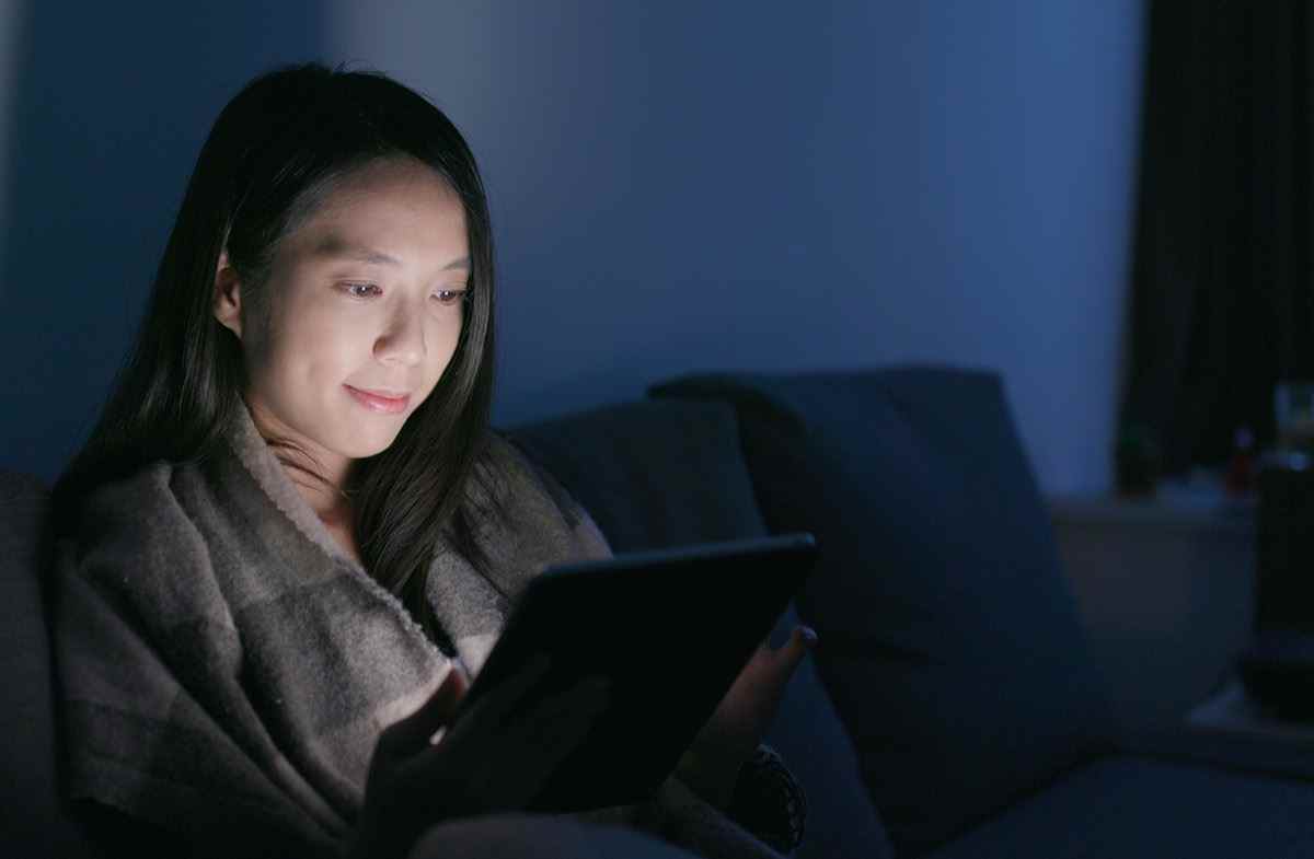 Frau schaut zu Hause auf Tablet-Computer