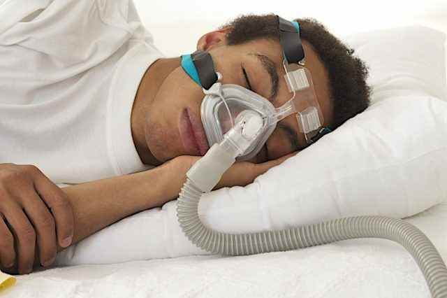 Mann schläft mit Apnoe und CPAP-Gerät