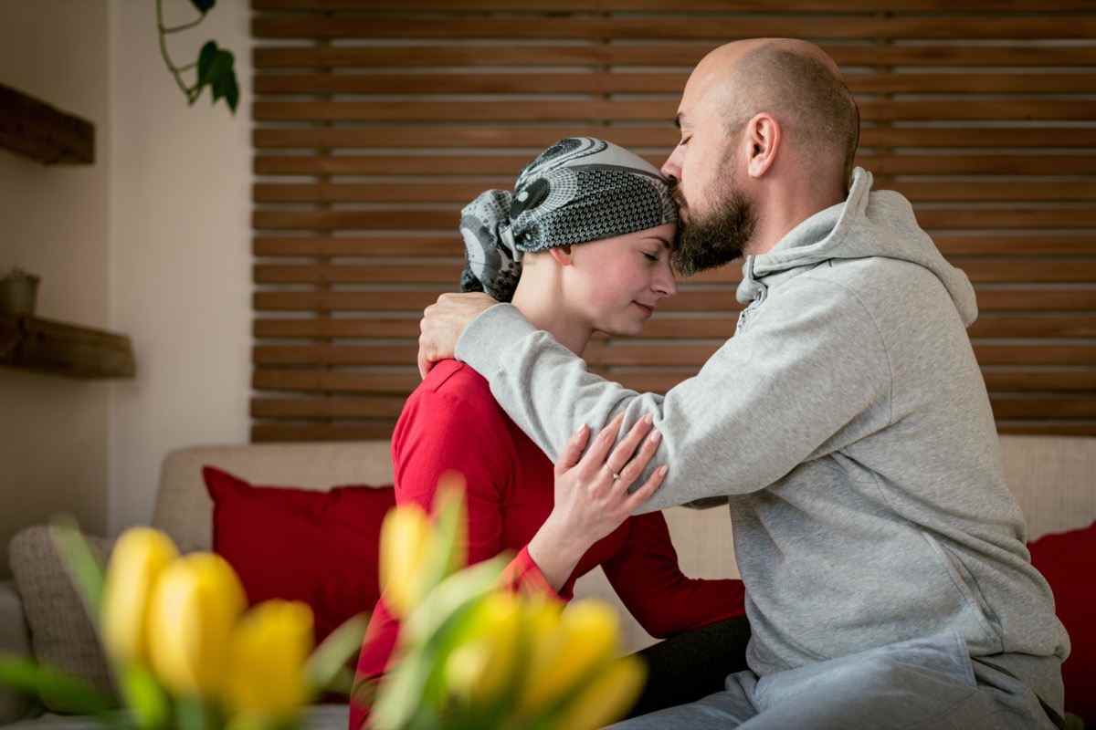 Unterstützender Ehemann, der seine Frau, Krebspatientin, nach der Behandlung im Krankenhaus küsst