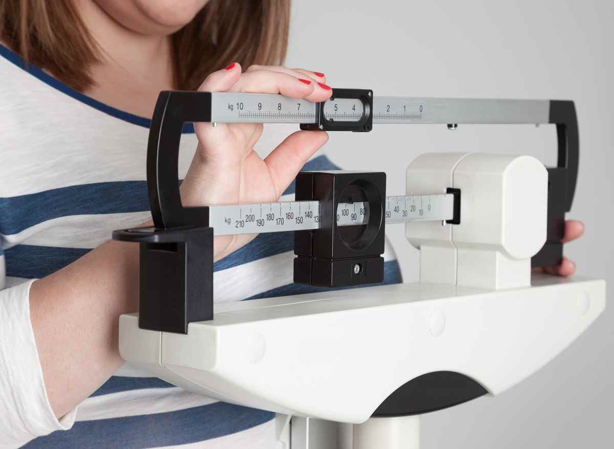 Frau wiegt sich übergewichtig auf der Waage