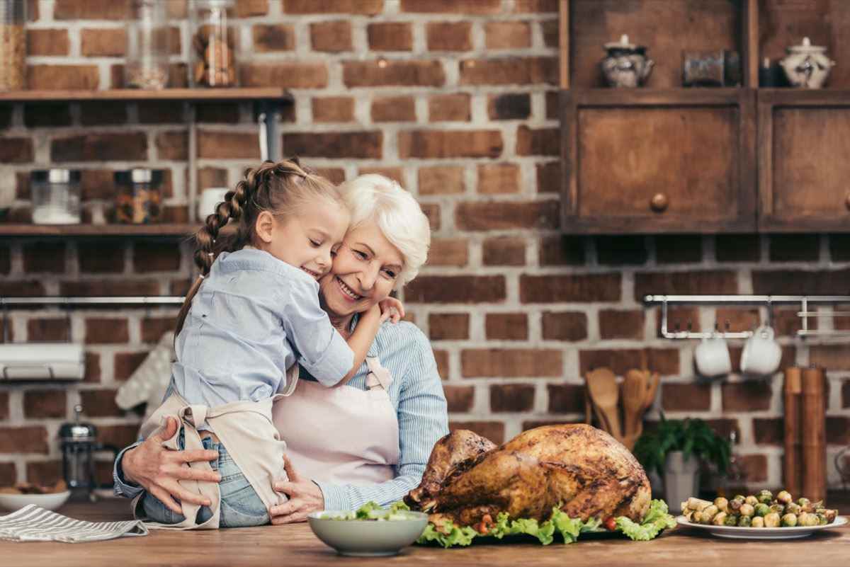 Großmutter und Enkelin umarmen sich in der Küche und betrachten frisch zubereiteten Truthahn zum Erntedankfest?