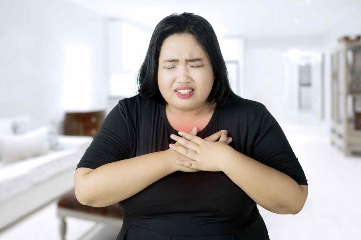 Übergewichtige Frau, die einen Herzinfarkt erleidet, während sie ihre Brust berührt