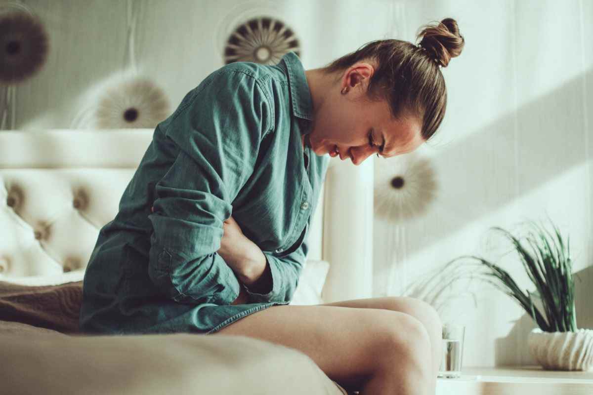 Junge verärgerte gestresste Frau, die während der Menstruation an Bauch- und Magenschmerzen leidet, PMS im Zimmer zu Hause.  Entzündung und Infektion.  Lebensmittelvergiftung