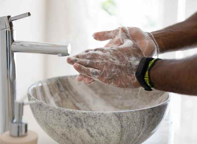 Person, die sich die Hände in einer modernen Marmorspüle wäscht