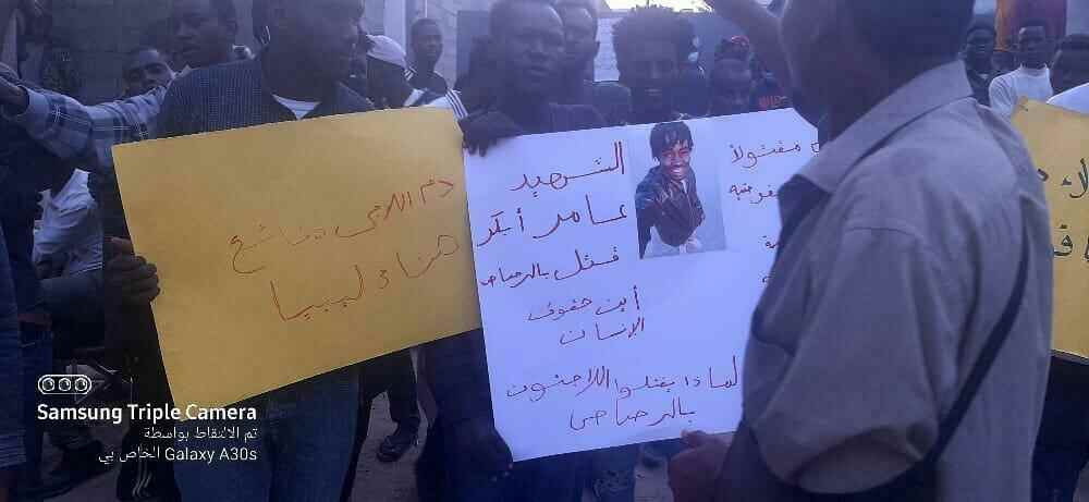 Migranten halten Schilder mit der Forderung nach Gerechtigkeit nach der Ermordung des jungen Sudanesen Amer Baker vor dem UNHCR-Büro hoch.