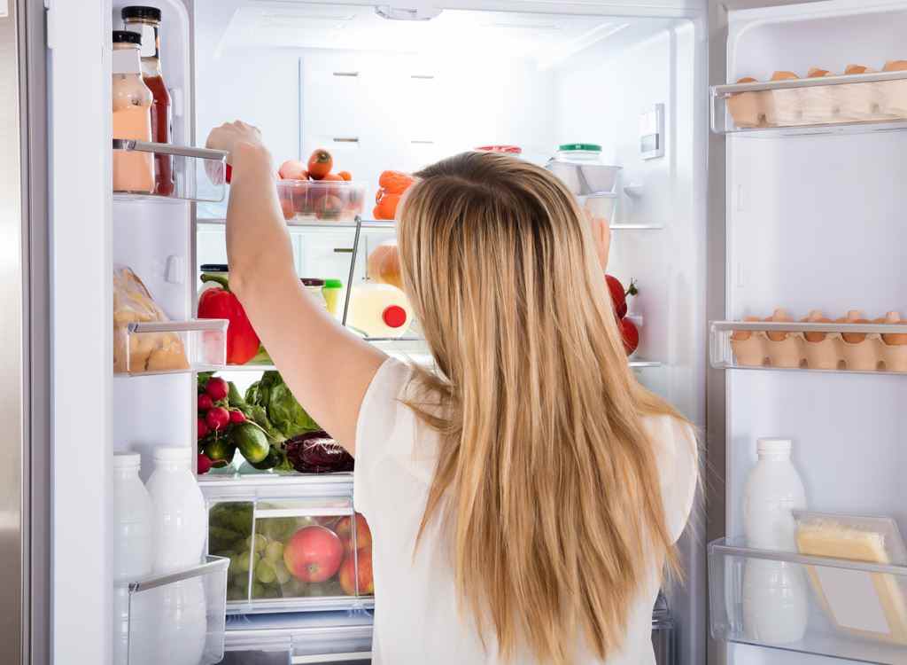 Hungrige Frau auf der Suche nach Essen im Kühlschrank