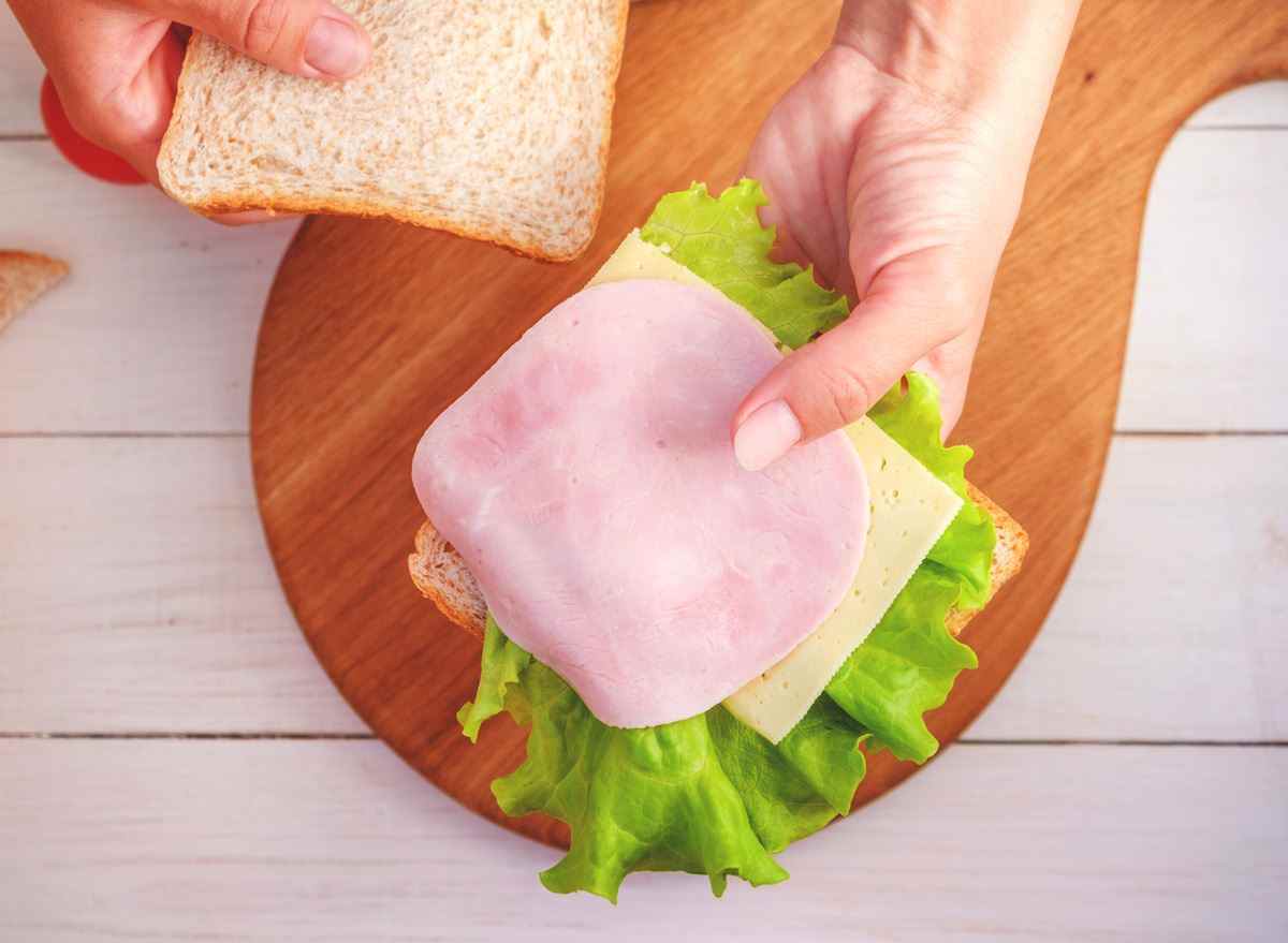 Frau macht Sandwich-Brot-Salat-Käse-Deli-Fleisch zum Mittagessen