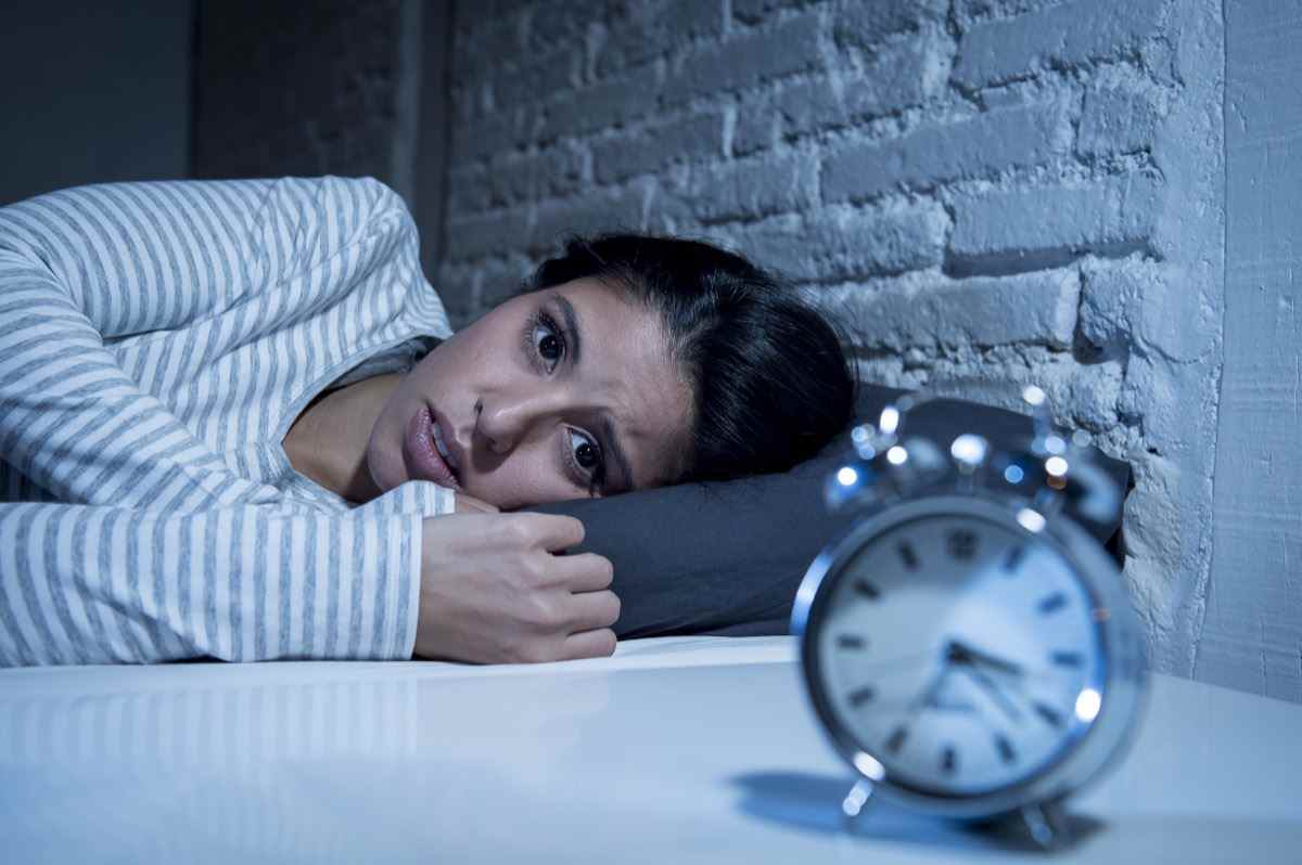 Hispanische Frau zu Hause Schlafzimmer liegt spät in der Nacht im Bett und versucht zu schlafen, leidet an Schlaflosigkeit, Schlafstörungen oder hat Angst vor Albträumen, die traurig, besorgt und gestresst aussehen