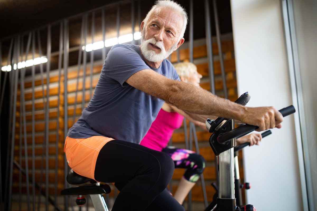Reife, fitte Leute, die im Fitnessstudio Fahrrad fahren, die Beine trainieren und Cardio-Workout-Fahrräder machen?