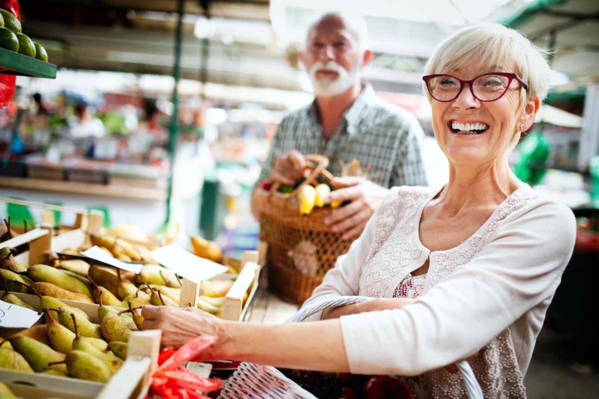 älteres Ehepaar auf dem Markt, das Essen kauft