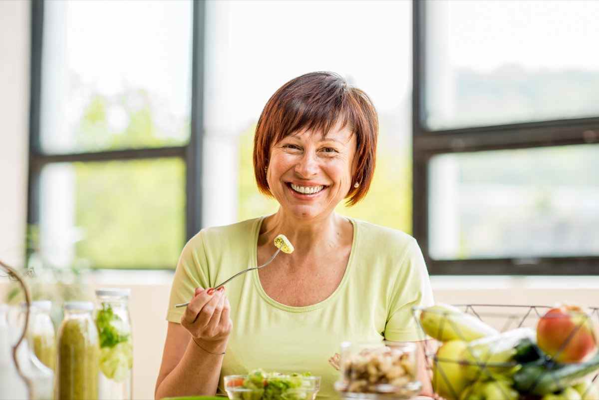 ältere Frau mit grünem gesundem Essen auf dem Tisch