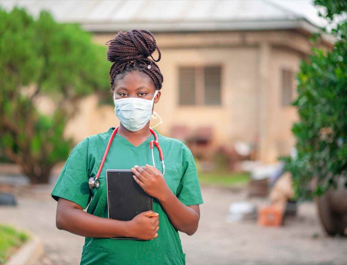 Afrikanisches Gesundheitspersonal, das Tablet mit ihrem Stethoskop um den Hals hält