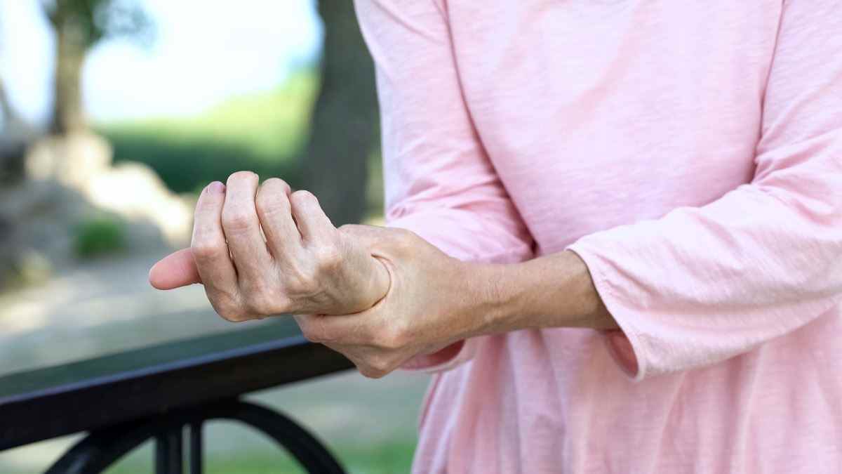 Alte Frau, die tauben Arm ausdehnt, Muskelschwäche im Alter, Arthritis