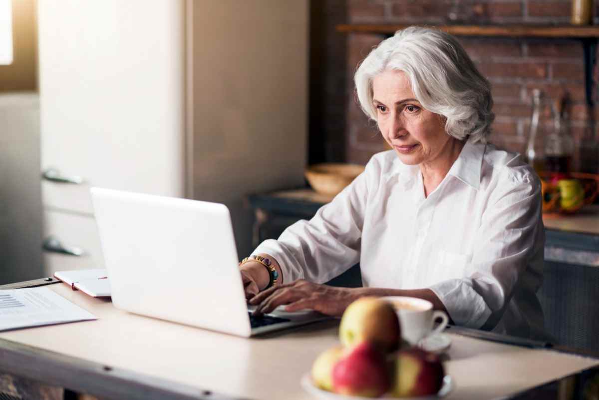 ältere Frau, die auf Laptop schaut