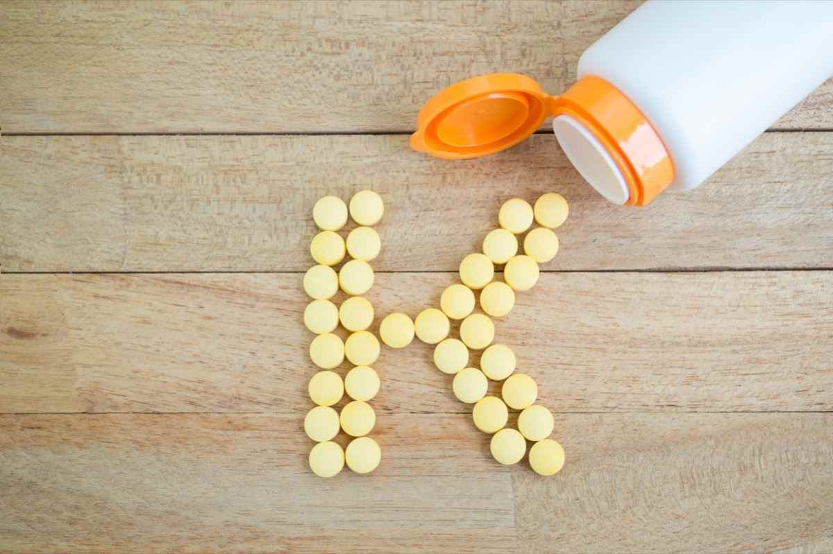 Gelbe Pillen, die Form zu K-Alphabet auf Holzhintergrund bilden