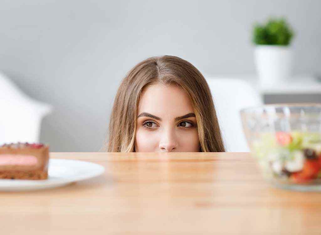 Woman craving junk food over salad