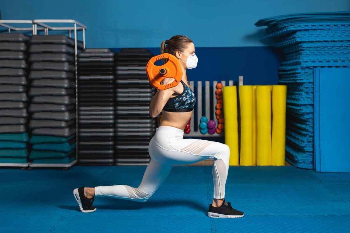 woman doing lunges at the gym wearing n95 face mask