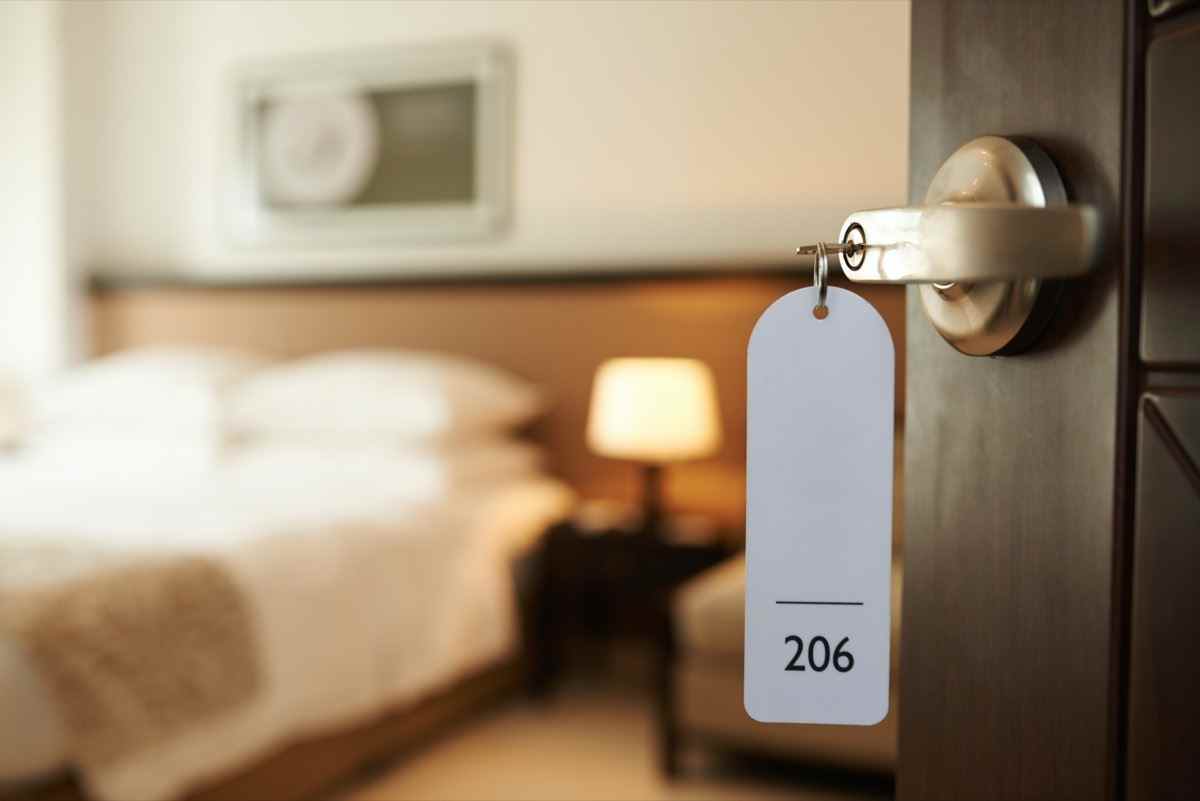 Geöffnete Tür des Hotelzimmers mit Schlüssel im Schloss