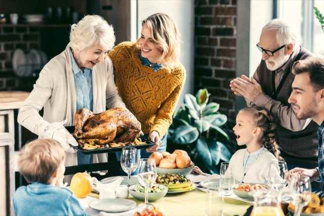 Großmutter trägt Truthahn für die Familie beim Thanksgiving-Dinner