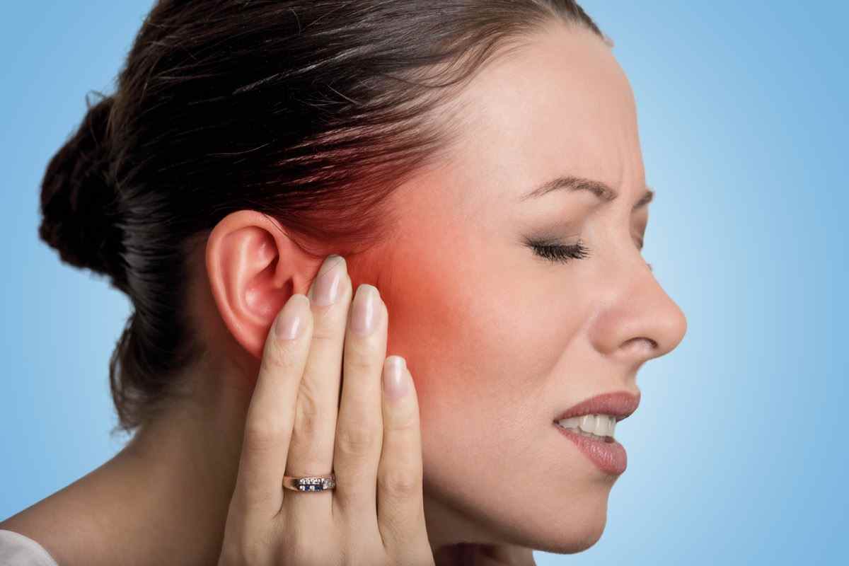 Frau mit Ohrenschmerzen, die ihren schmerzenden Kopf berührt