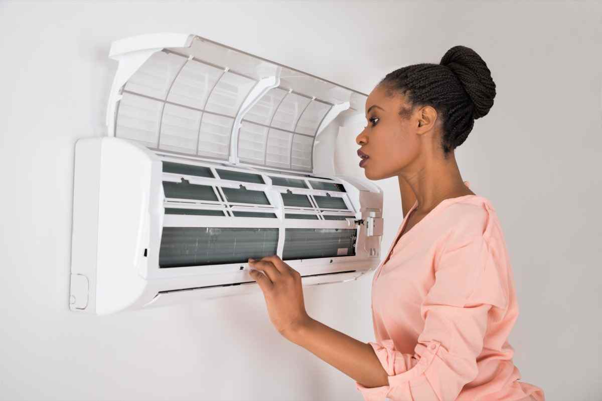 Frau überprüft die Klimaanlage zu Hause