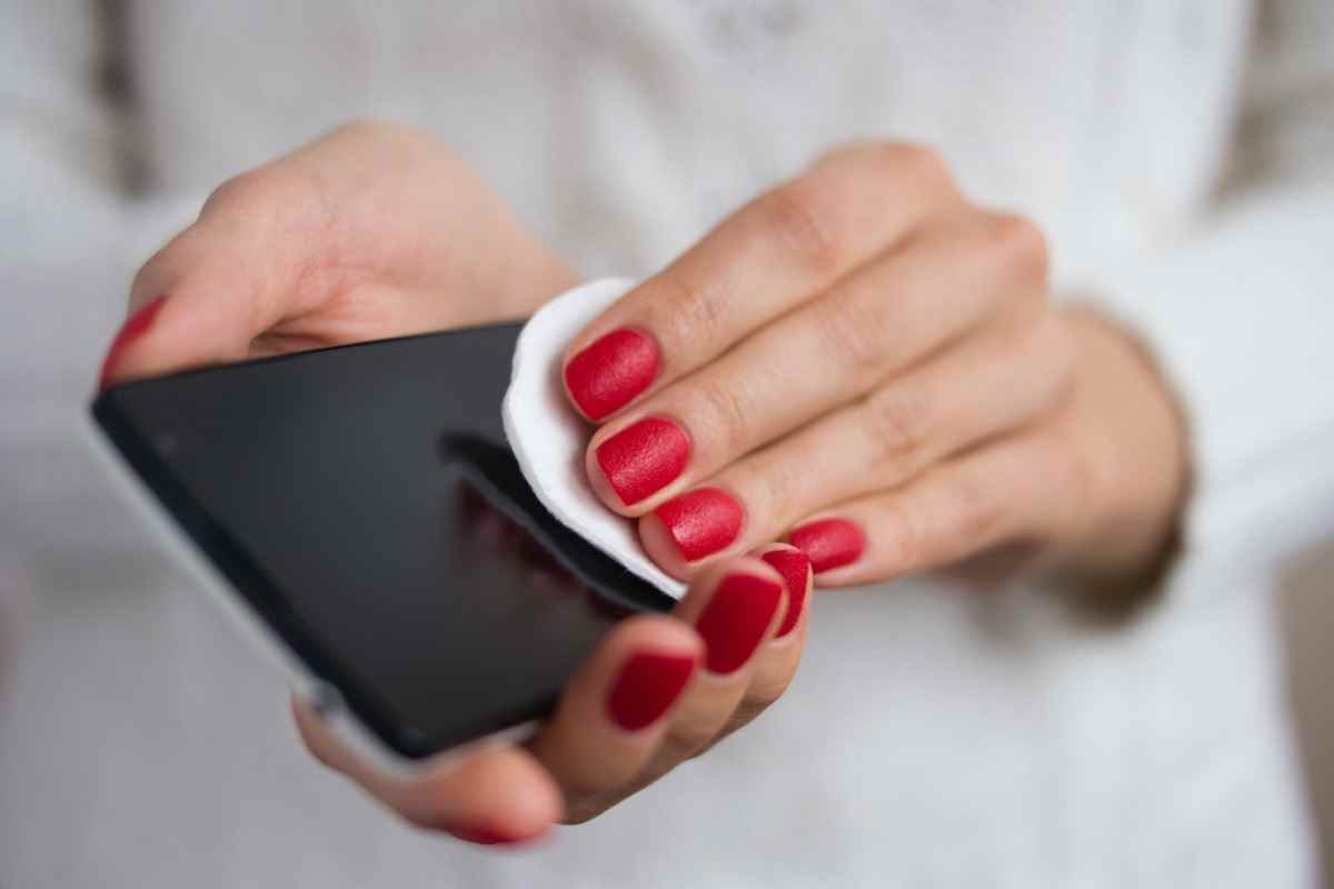 Weibliche Hände, die ein Mobiltelefon halten und das Bildschirmtuch abwischen
