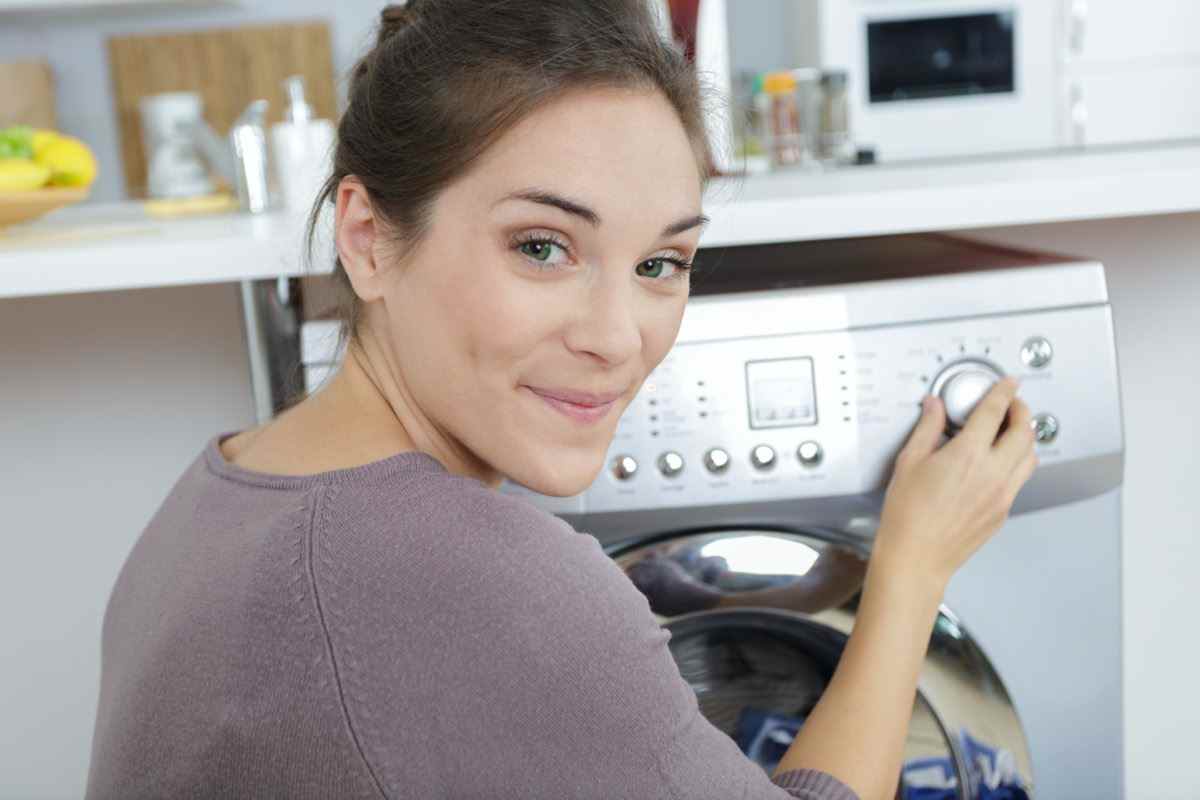 Porträt einer Frau mit Einstellrad an ihrer Waschmaschine