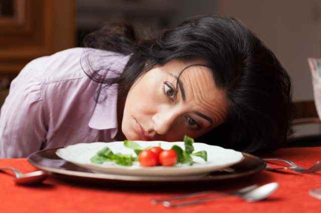 Frau, die auf einen kleinen Salat schaut, ist müde von der Diät