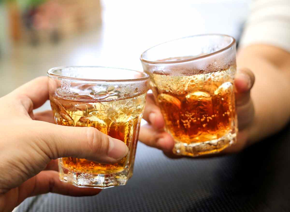 Männer jubeln mit Gläsern eines Whisky-Soda-Alkohol-Cocktailgetränks