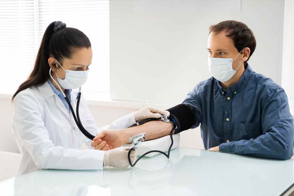 Arzt überprüft hohen Blutdruck in der Gesichtsmaske