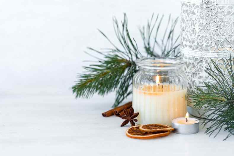 Eine Kerze neben weihnachtlichen Gewürzen/Aromen.