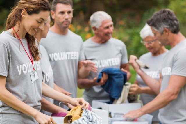 Glücklicher Freiwilliger, der an einem sonnigen Tag die Spendenbox betrachtet