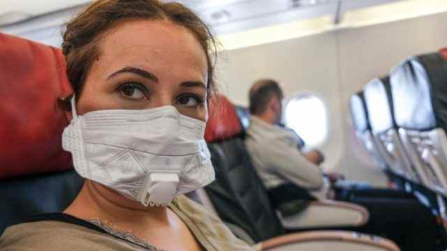 Frau, die mit einem Flugzeug mit einer Maske wegen ansteckender Krankheiten reist