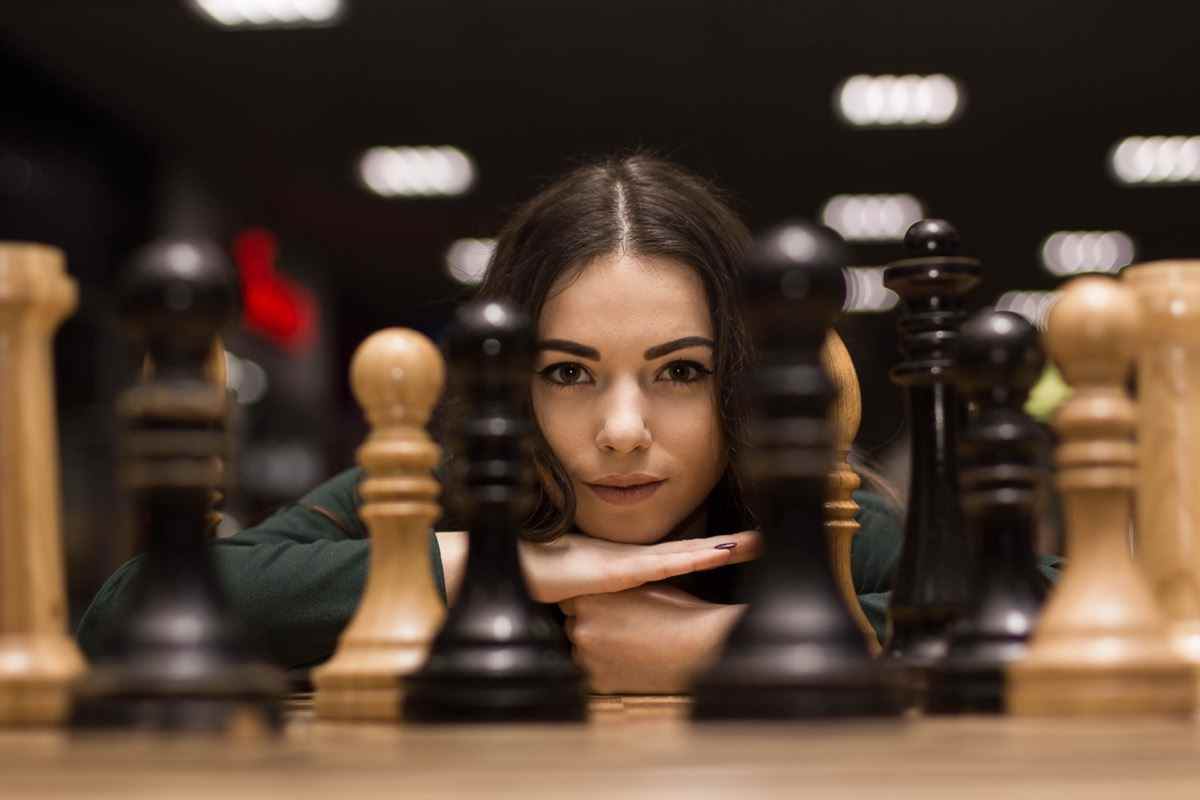 Frau, die Schachfiguren betrachtet.