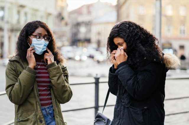 mit Niesen auf der Stadtstraße, Frau ohne Schutzmaske beim Verbreiten von Grippe, Erkältung, Covid-19