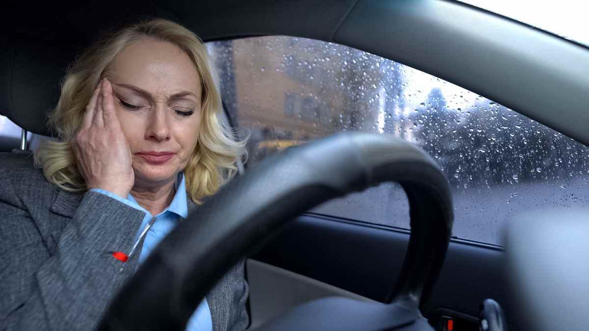 Reife Geschäftsfrau, die an einem regnerischen Tag in einem Auto sitzt