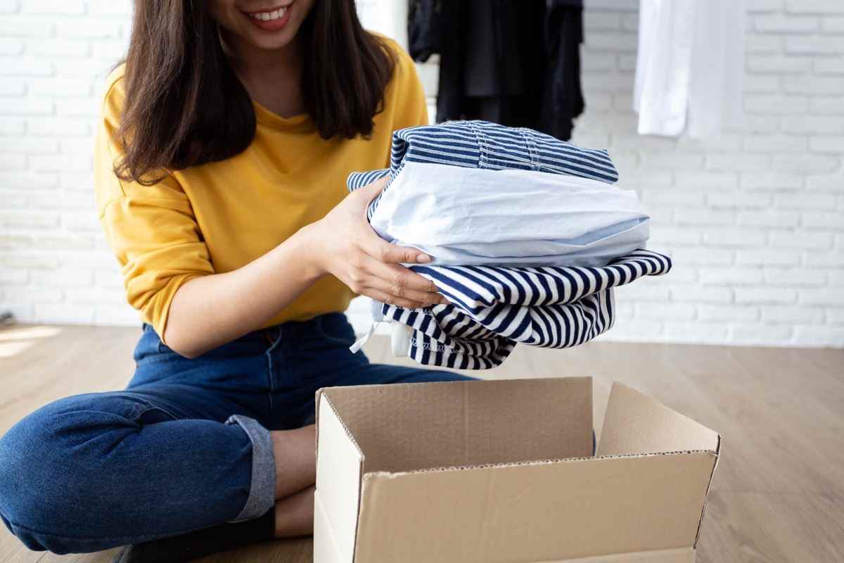 Woman holding Clothes with Donate Box In her room, Donation Concept