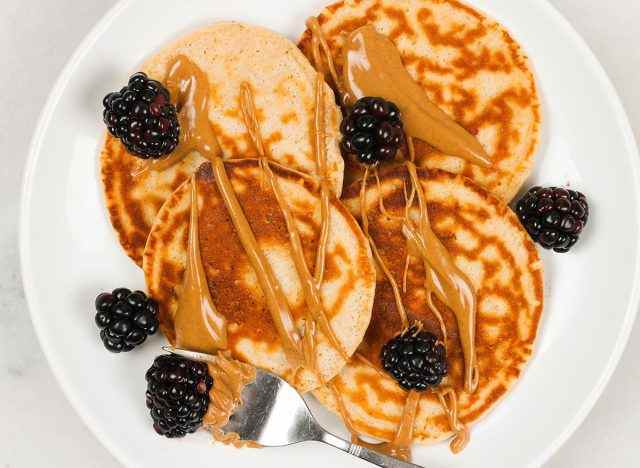 Protein Pancakes mit Erdnussbutter und Brombeeren auf einem weißen Teller