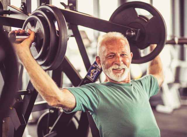 älterer-mann-heben-schwere-hantel-im-gym-mager-körper-nach-60