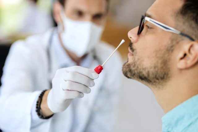 Nahaufnahme eines jungen Mannes, der während der Coronavirus-Epidemie einen PCR-Test in der Arztpraxis erhält.