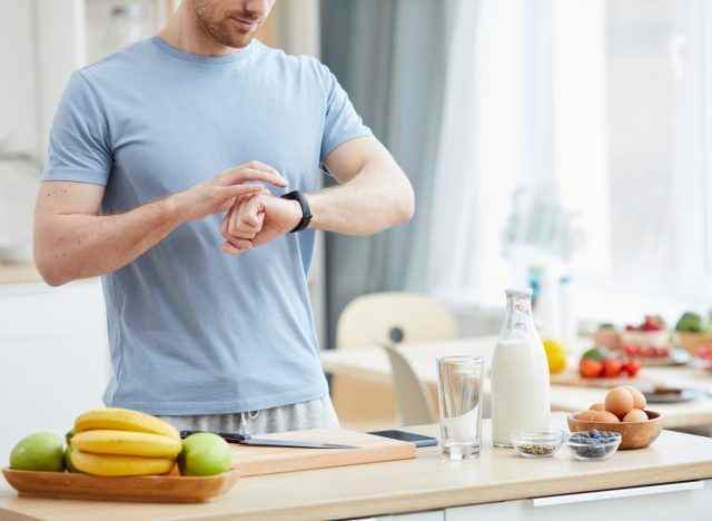 man checking watch before eating breakfast