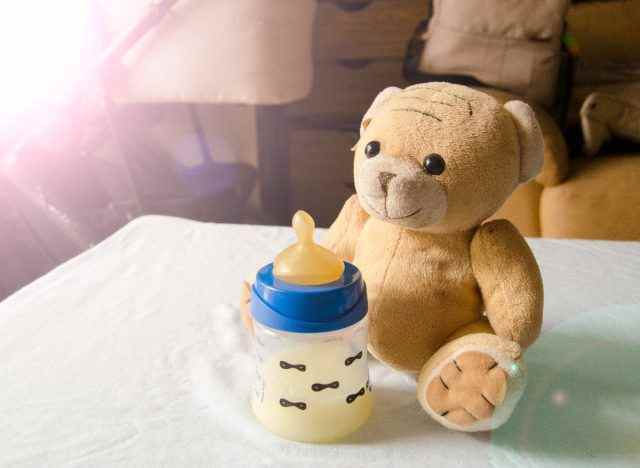 Milchflasche neben Teddybär im Kinderzimmer