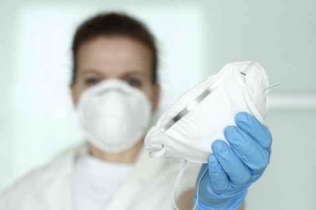 Sanitäter, Krankenschwester mit Gesichtsmaske und blauen Nitridhandschuhen, die sich eine N95-Maske teilen.