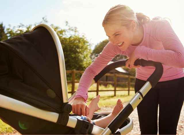 Frau in Trainingskleidung mit neuem Baby im Kinderwagen