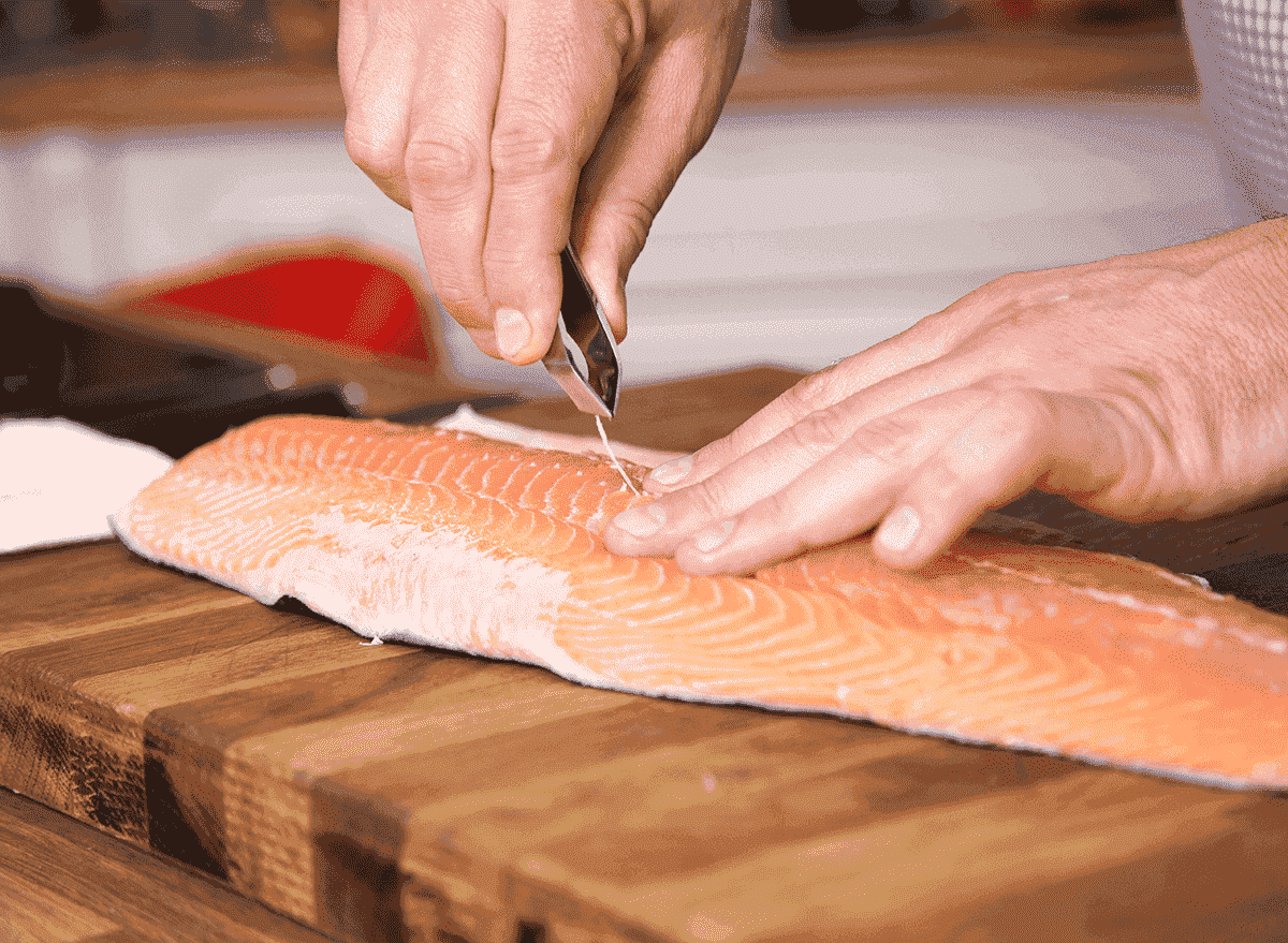 man using tool to debone salmon skin