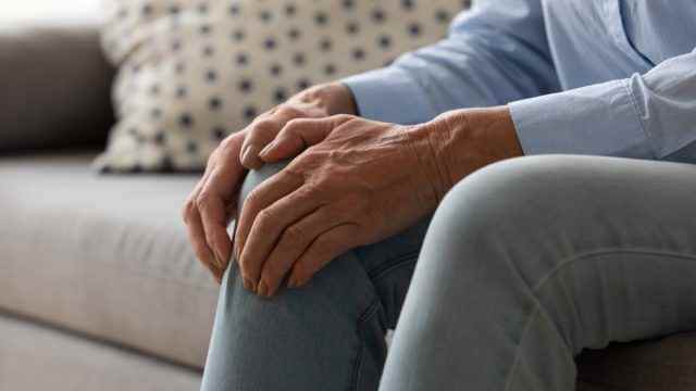 ältere frau auf couch mit knieschmerzen