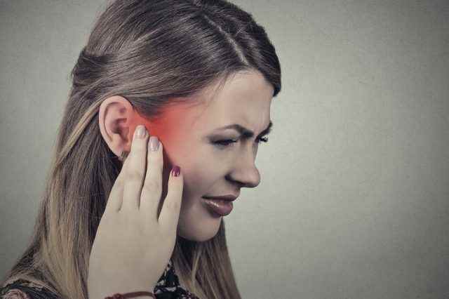 Closeup Seitenprofil kranke junge Frau mit Ohrenschmerzen, die ihren schmerzhaften Kopfbügel berühren